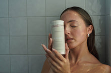 Load image into Gallery viewer, Woman holding a skincare product in a bathroom setting