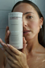 Load image into Gallery viewer, Woman holding a 'Kind Bod' product container in front of her face.