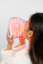 Load image into Gallery viewer, Person holding a pink LED face mask against a white background
