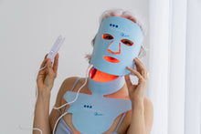 Load image into Gallery viewer, Person wearing a blue LED face and body mask with visible branding.