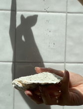 Load image into Gallery viewer, Hand holding a piece of stone with a shadow of a deer on a tiled wall
