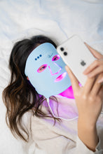 Load image into Gallery viewer, Person wearing a LED face mask and using a phone on a white background
